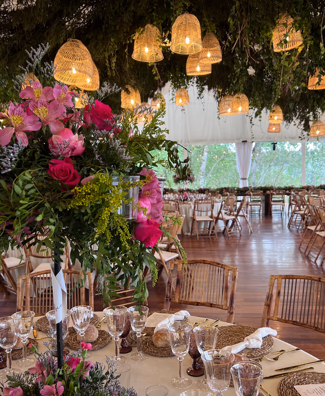 Salón decorado con flores rosas y lámparas de ratán preparado para una celebración