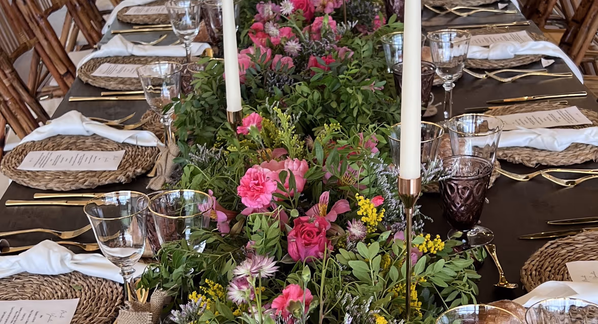Mesa imperial vestida con flores silvestres y velas, preparada para una degustación de menú