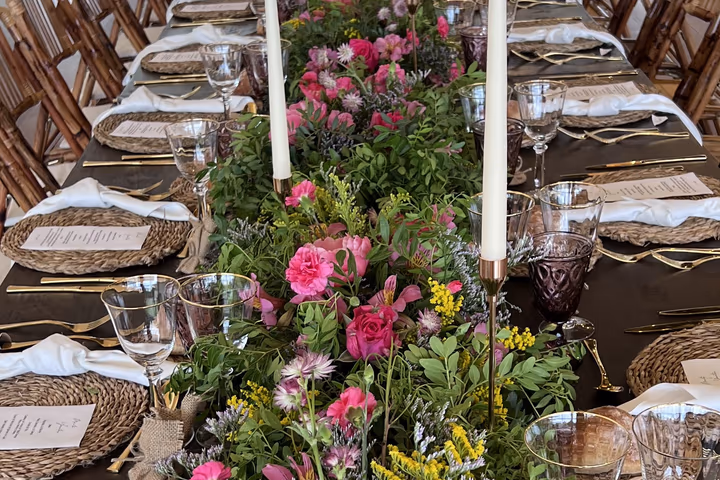 Mesa imperial vestida con flores silvestres y velas, preparada para una degustación de menú